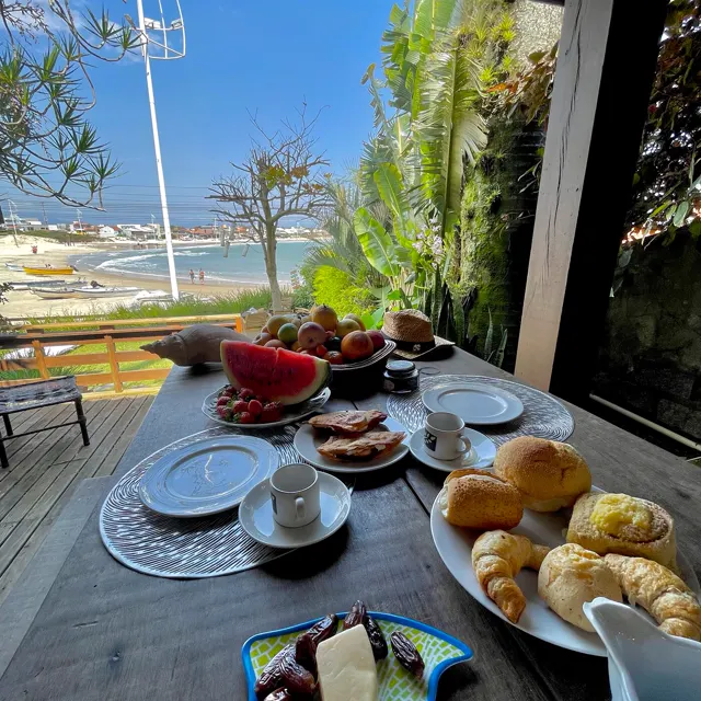 Mesa de café posta no deck, com a praia ao fundo