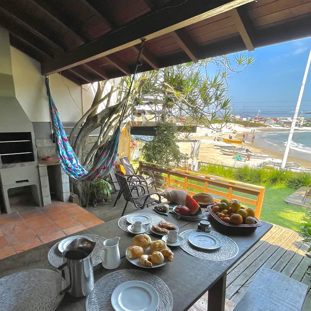 Deck com rede, mesa e churrasqueira, com vista da praia