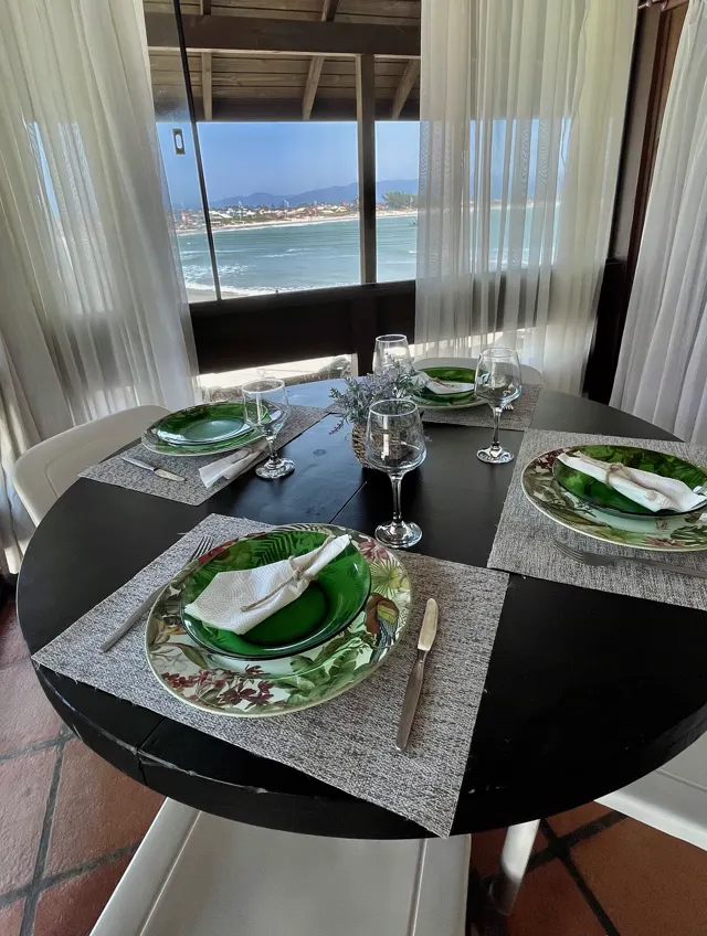 Mesa posta com vista para o mar pela janela