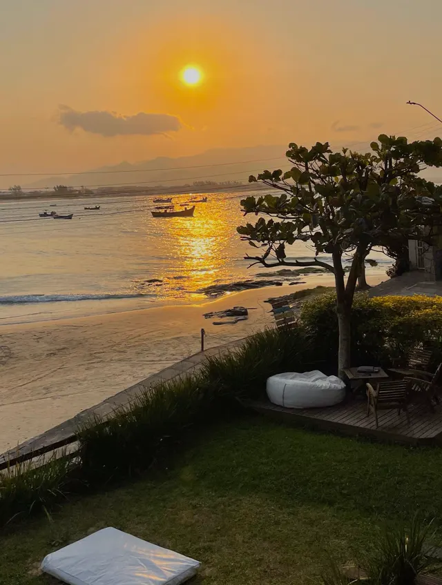 Pôr do sol sobre o mar visto do gramado em frente ao espaço Pé na Areia